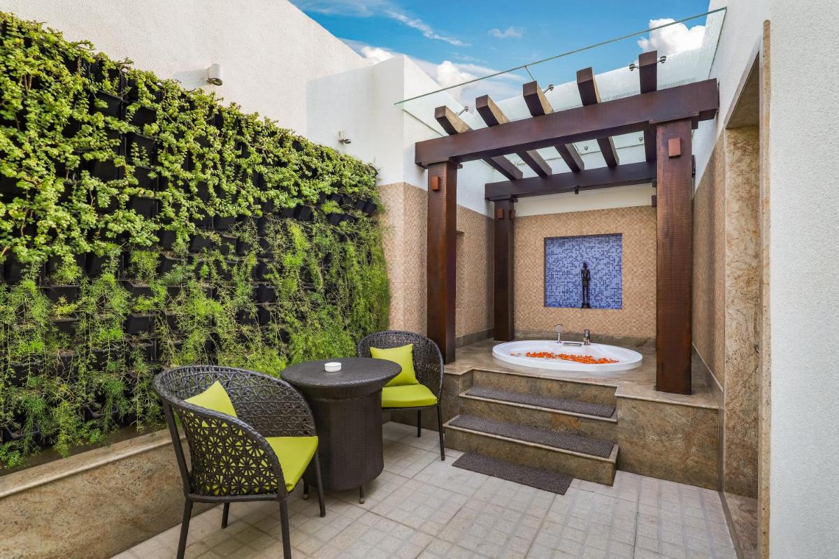 a patio with a bath tub and chairs and a table at Lemon Tree Premier, Delhi Airport in New Delhi a patio with a bath tub and chairs and a table at Lemon Tree Premier, Delhi Airport in New Delhi