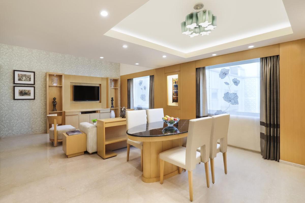 a dining room and living room with a table and chairs at Lemon Tree Premier, Delhi Airport in New Delhi a dining room and living room with a table and chairs at Lemon Tree Premier, Delhi Airport in New Delhi