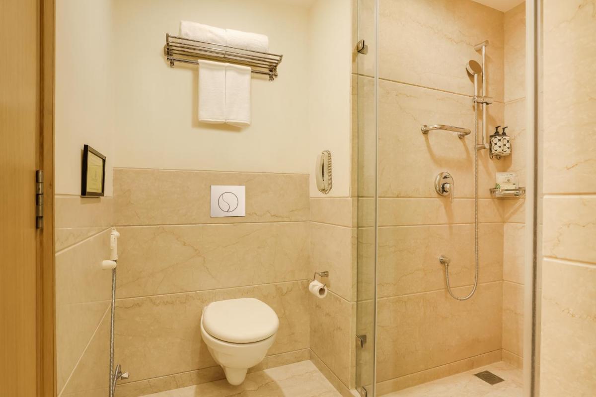 a bathroom with a toilet and a glass shower at Lemon Tree Premier, Delhi Airport in New Delhi a bathroom with a toilet and a glass shower at Lemon Tree Premier, Delhi Airport in New Delhi