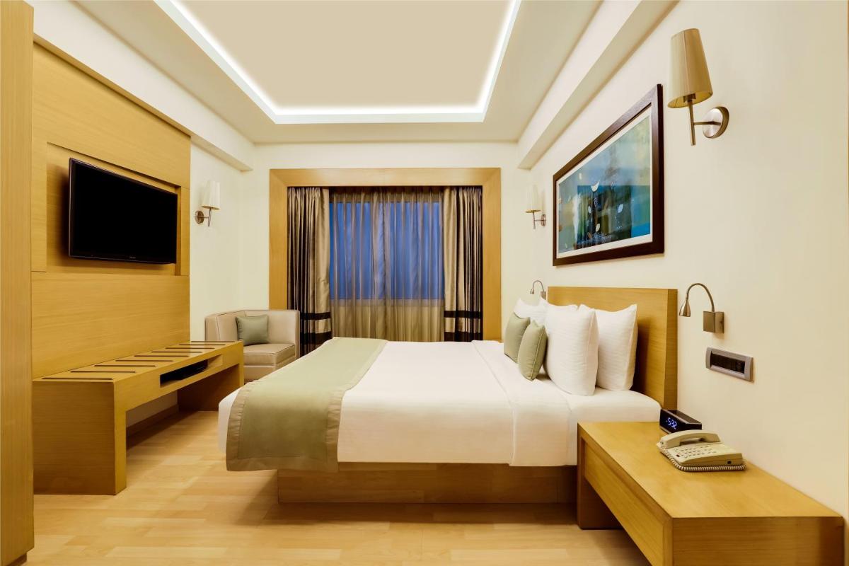 a hotel room with a bed and a television at Lemon Tree Premier, Delhi Airport in New Delhi a hotel room with a bed and a television at Lemon Tree Premier, Delhi Airport in New Delhi