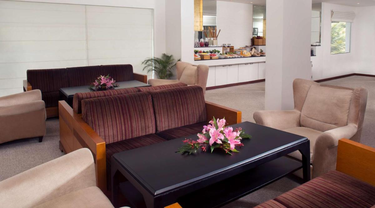 a waiting room with couches and tables and flowers on a table at Radisson Blu Kochi in Cochin