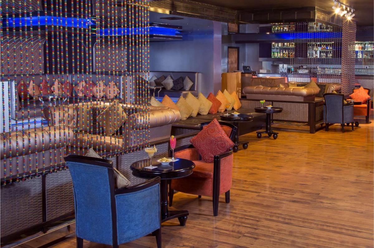 a restaurant with tables and couches and a bar at Radisson Blu Kochi in Cochin