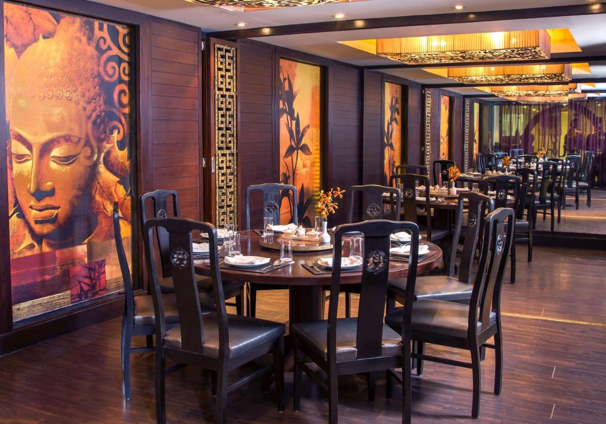 a dining room with tables and chairs and a painting at Radisson Blu Kochi in Cochin