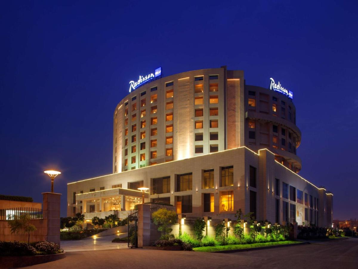 a hotel building with a sign on top of it at Radisson Blu Hotel New Delhi Dwarka in New Delhi a hotel building with a sign on top of it at Radisson Blu Hotel New Delhi Dwarka in New Delhi