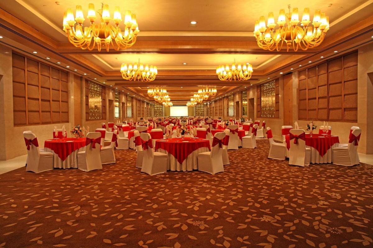 a banquet hall with tables and chairs and chandeliers at Radisson Blu Hotel New Delhi Dwarka in New Delhi a banquet hall with tables and chairs and chandeliers at Radisson Blu Hotel New Delhi Dwarka in New Delhi