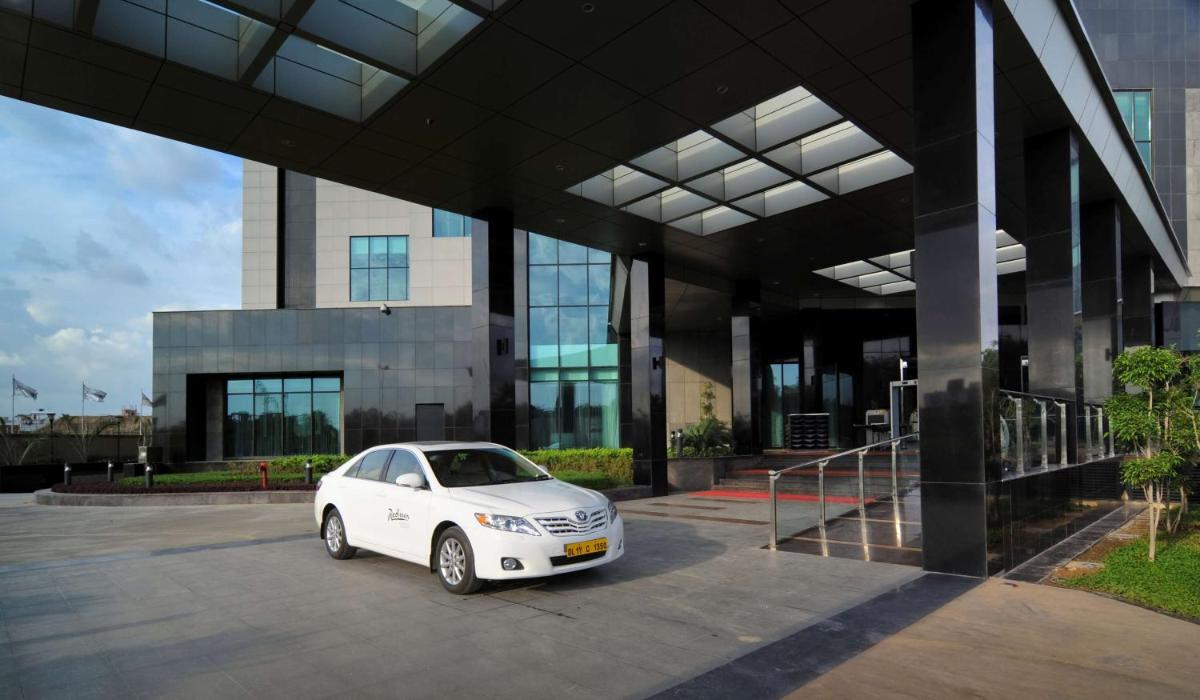 a white car parked in front of a building at Radisson Blu Hotel New Delhi Paschim Vihar in New Delhi a white car parked in front of a building at Radisson Blu Hotel New Delhi Paschim Vihar in New Delhi