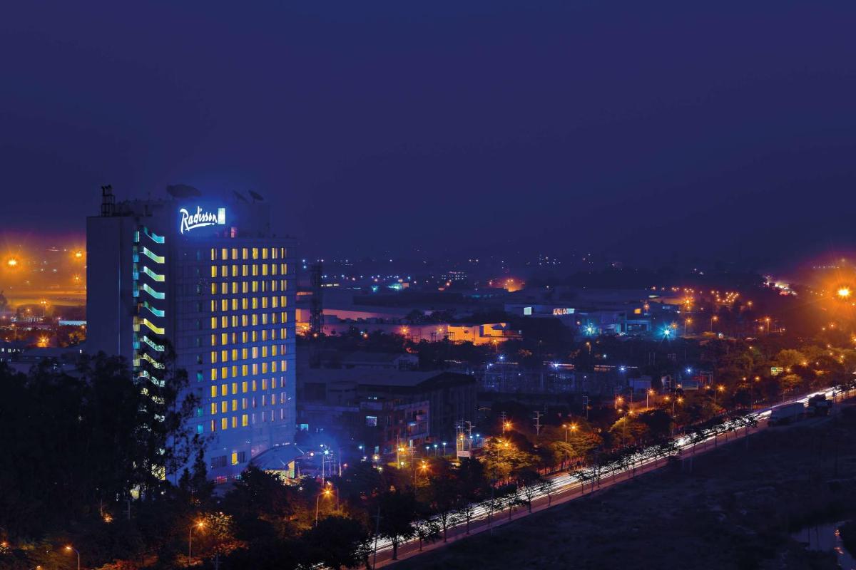 a lit up city at night with a tall building at Radisson Blu Hotel, Greater Noida in Greater Noida