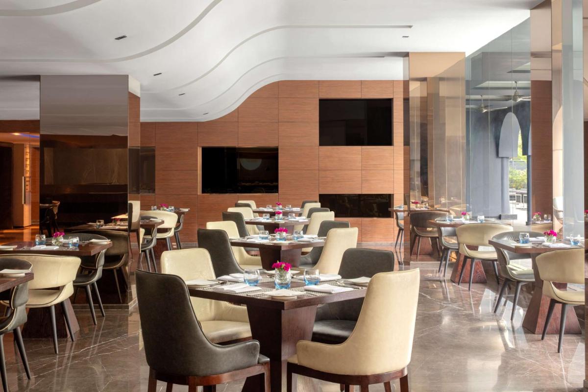 a restaurant with tables and chairs in a room at Radisson Blu Atria Bengaluru in Bengaluru a restaurant with tables and chairs in a room at Radisson Blu Atria Bengaluru in Bengaluru