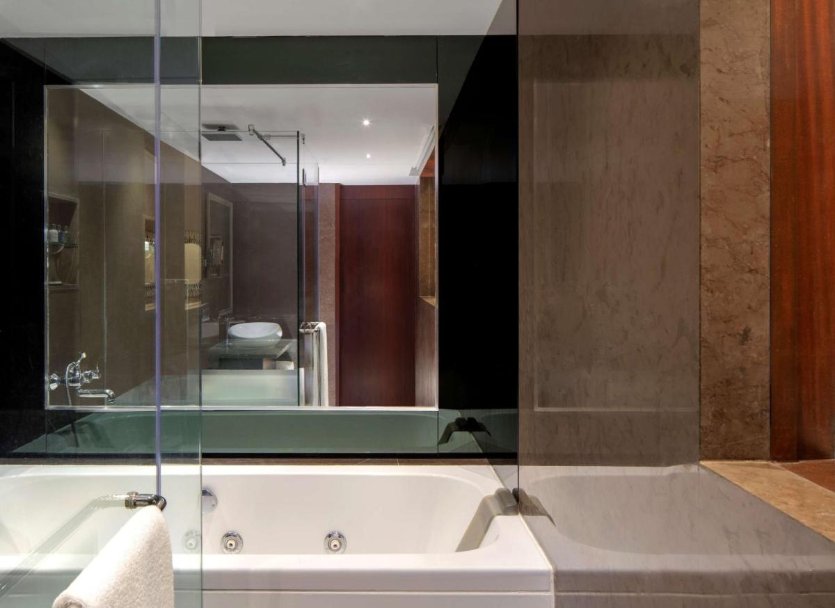 a bathroom with a bath tub with a large mirror at Radisson Blu Atria Bengaluru in Bengaluru a bathroom with a bath tub with a large mirror at Radisson Blu Atria Bengaluru in Bengaluru
