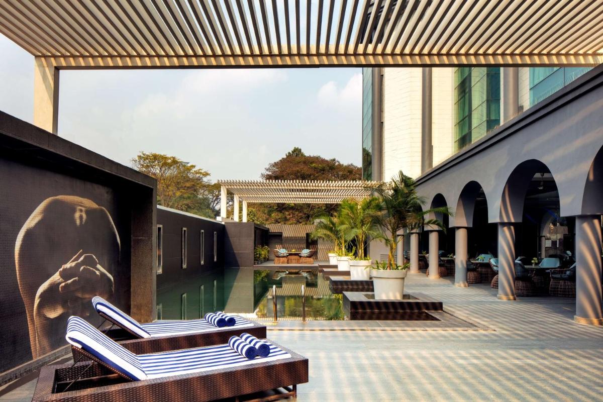 a resort with lounge chairs and a swimming pool at Radisson Blu Atria Bengaluru in Bengaluru a resort with lounge chairs and a swimming pool at Radisson Blu Atria Bengaluru in Bengaluru