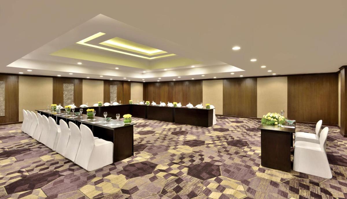 a conference room with a long table and white chairs at Radisson Blu Atria Bengaluru in Bengaluru a conference room with a long table and white chairs at Radisson Blu Atria Bengaluru in Bengaluru