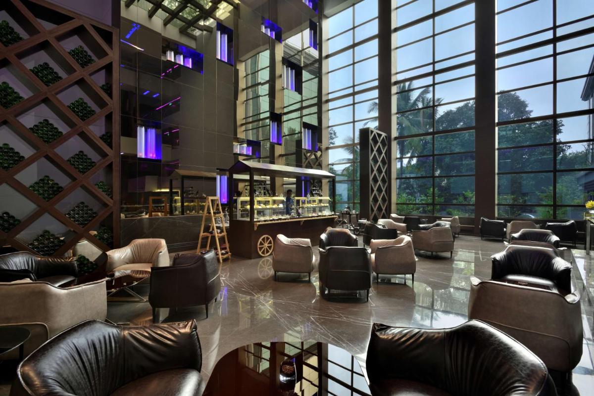 a lobby with chairs and a bar in a building at Radisson Blu Atria Bengaluru in Bengaluru a lobby with chairs and a bar in a building at Radisson Blu Atria Bengaluru in Bengaluru