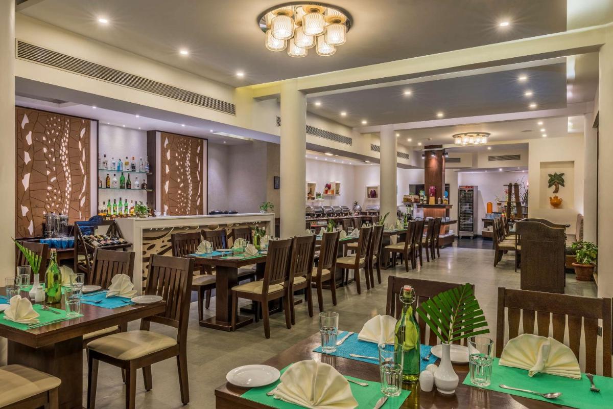 a restaurant with tables and chairs and a bar at Radisson Goa Candolim in Candolim