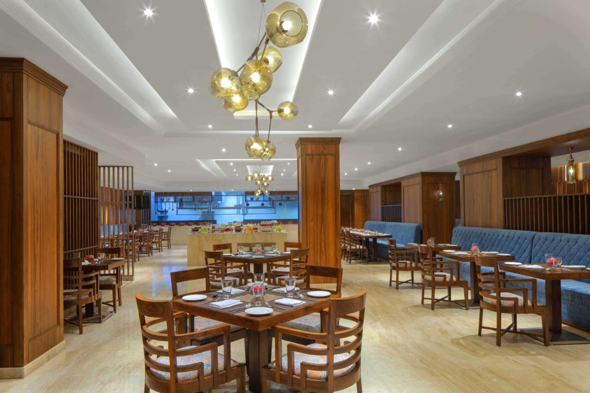 a dining room with wooden tables and chairs at Radisson Chandigarh Zirakpur in Chandīgarh