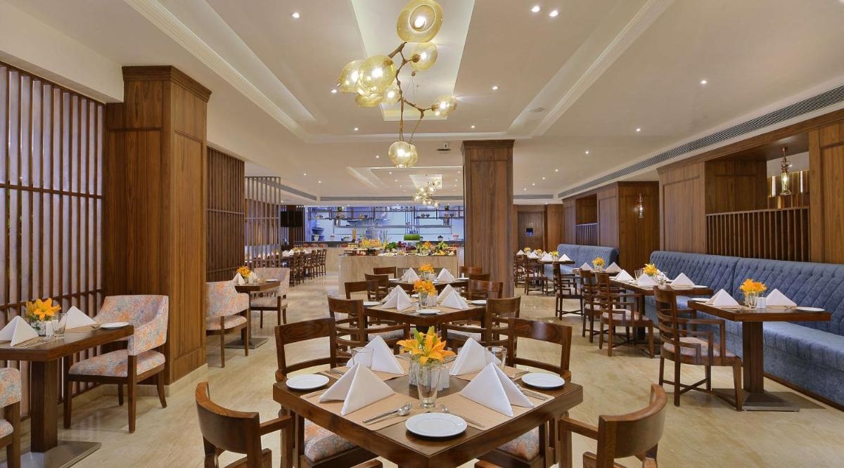 a dining room with tables and chairs and a restaurant at Radisson Chandigarh Zirakpur in Chandīgarh