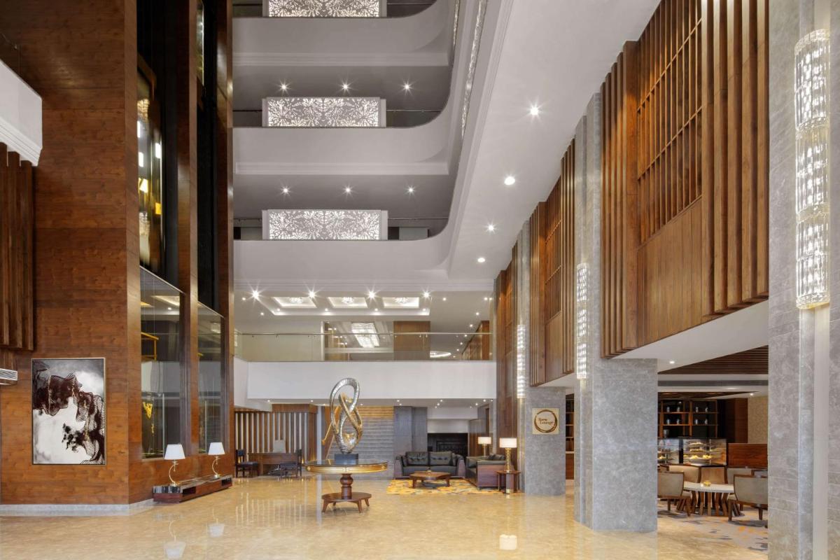 a lobby with tables and chairs in a building at Radisson Chandigarh Zirakpur in Chandīgarh +58 photos