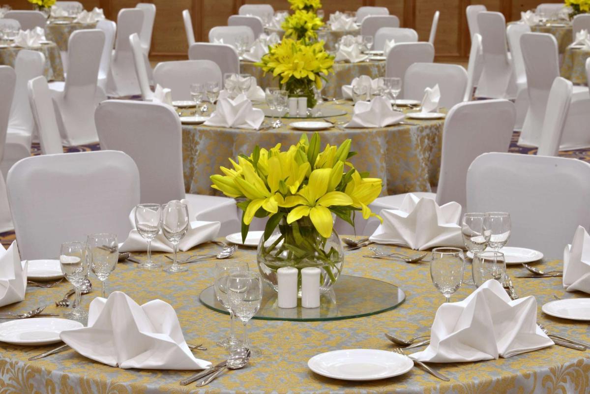 a table set for a wedding with yellow flowers in a vase at Radisson Chandigarh Zirakpur in Chandīgarh