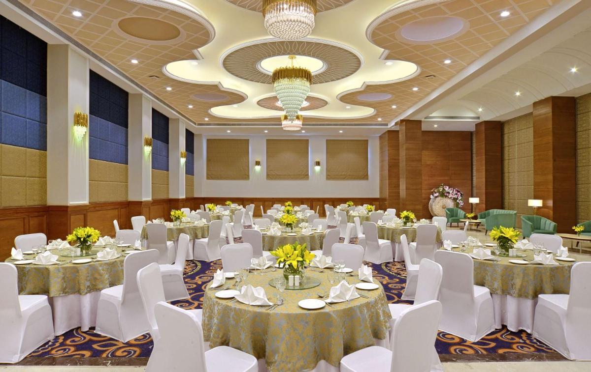 a banquet hall with white tables and white chairs at Radisson Chandigarh Zirakpur in Chandīgarh