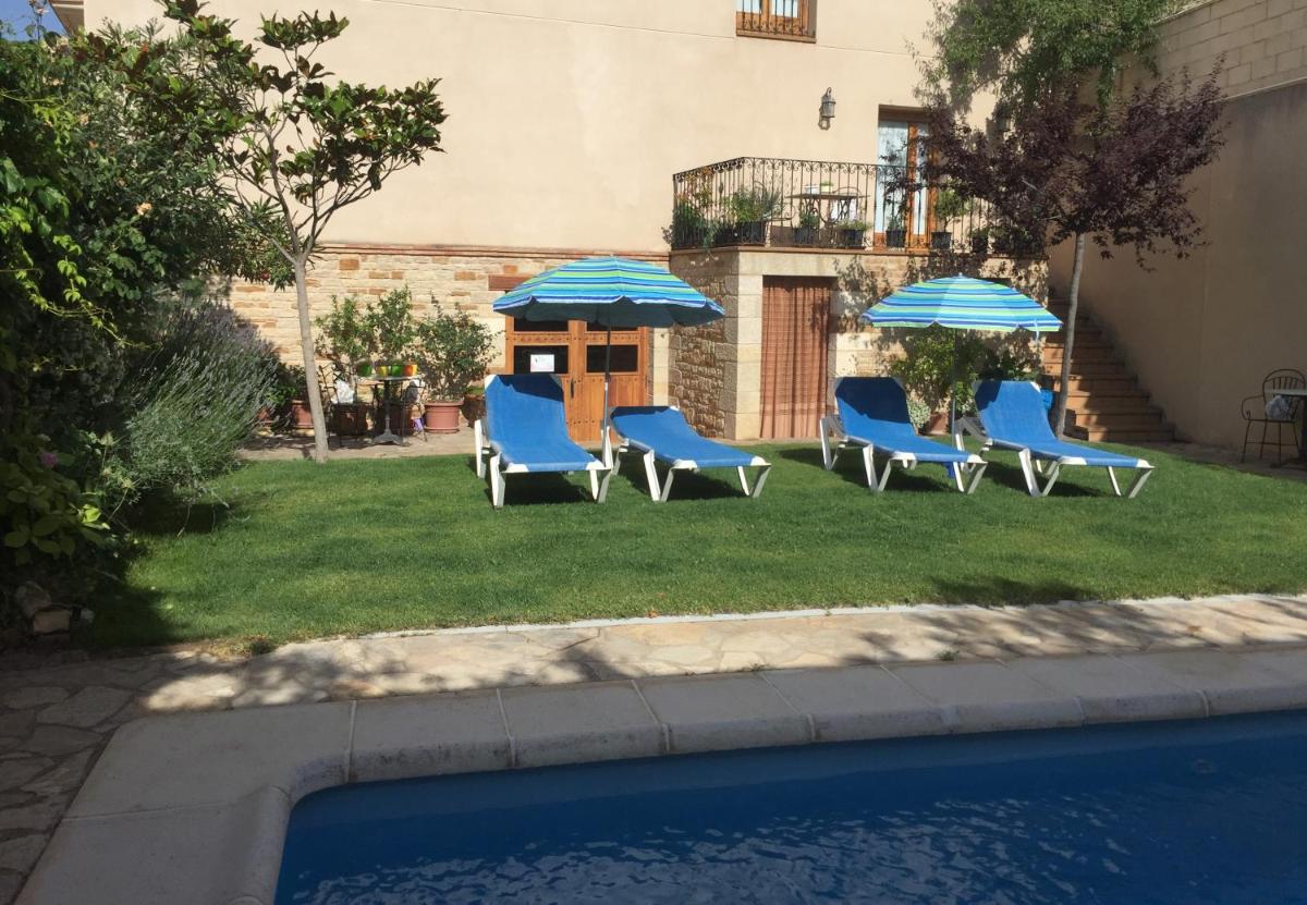 Un grupo de sillas y sombrillas junto a una piscina. en Hotel Castellote, en Castellote