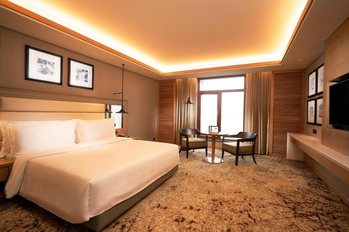 a hotel room with a large bed and a desk at The Residency Towers Puducherry in Puducherry