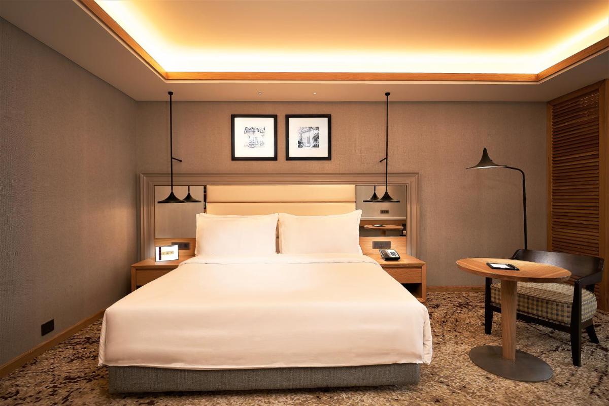 a hotel room with a large bed and a desk at The Residency Towers Puducherry in Puducherry
