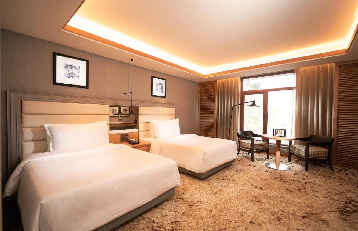 a hotel room with two beds and a desk at The Residency Towers Puducherry in Puducherry