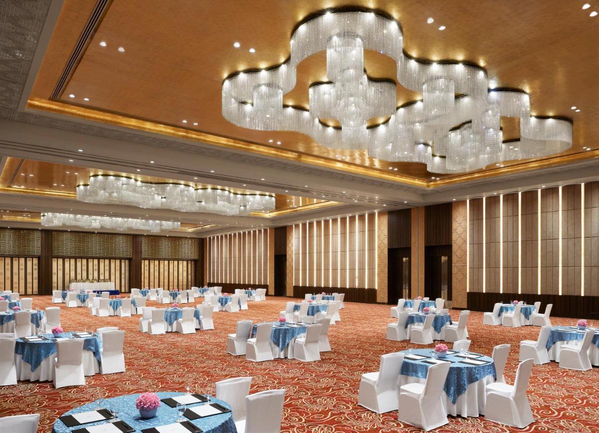 a banquet hall with white tables and chairs and a chandelier at Taj Agra in Agra
