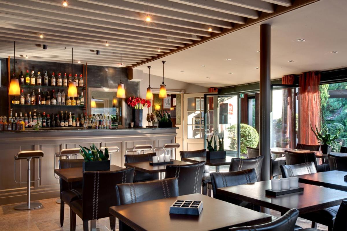 un restaurant avec des tables et des chaises et un bar dans l'établissement Hôtel Montmorency & Spa, à Carcassonne