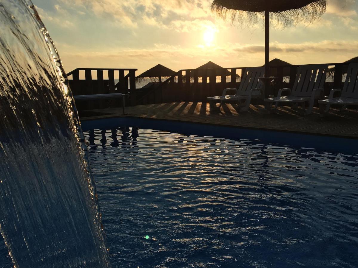 uma piscina com cadeiras e um guarda-sol e o pôr-do-sol em Promar - Eco Beach & Spa Hotel em Maceira