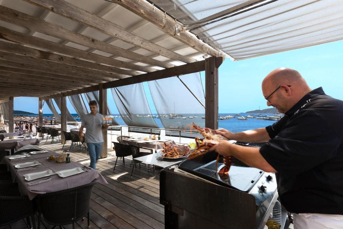 un homme fait cuire des aliments sur un gril sur un bateau dans l'établissement Le Pinarello, à Sainte-Lucie de Porto-Vecchio