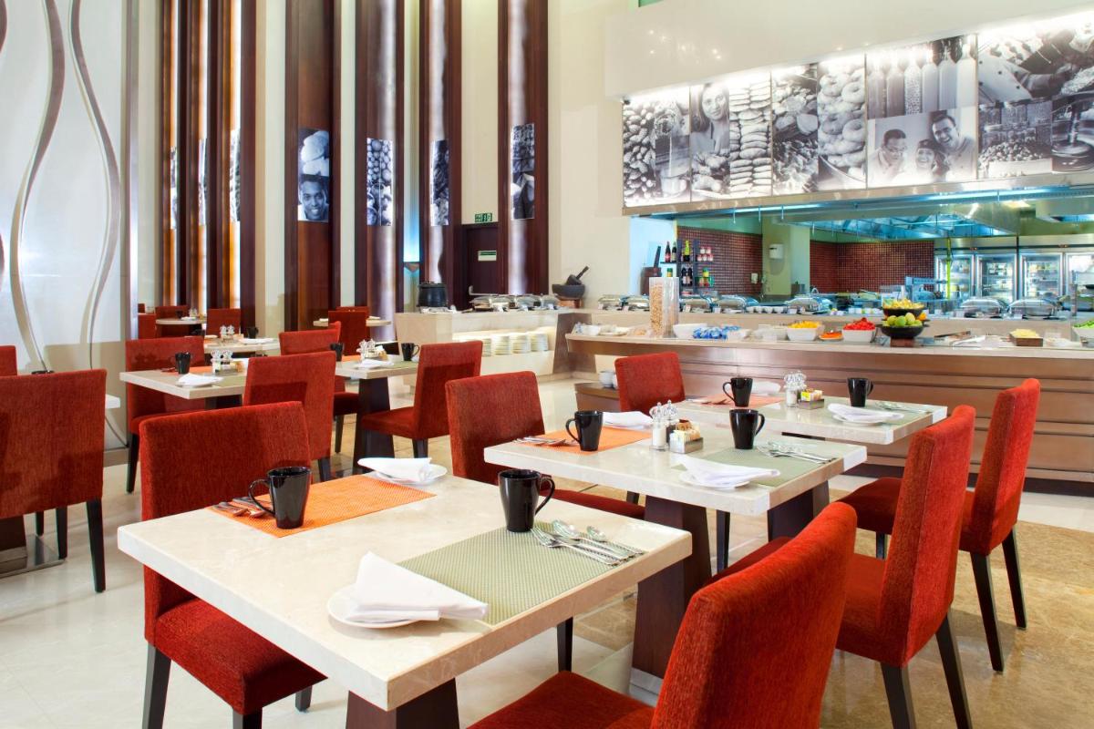 a dining room with tables and chairs and a restaurant at Holiday Inn Mumbai International Airport by IHG in Mumbai