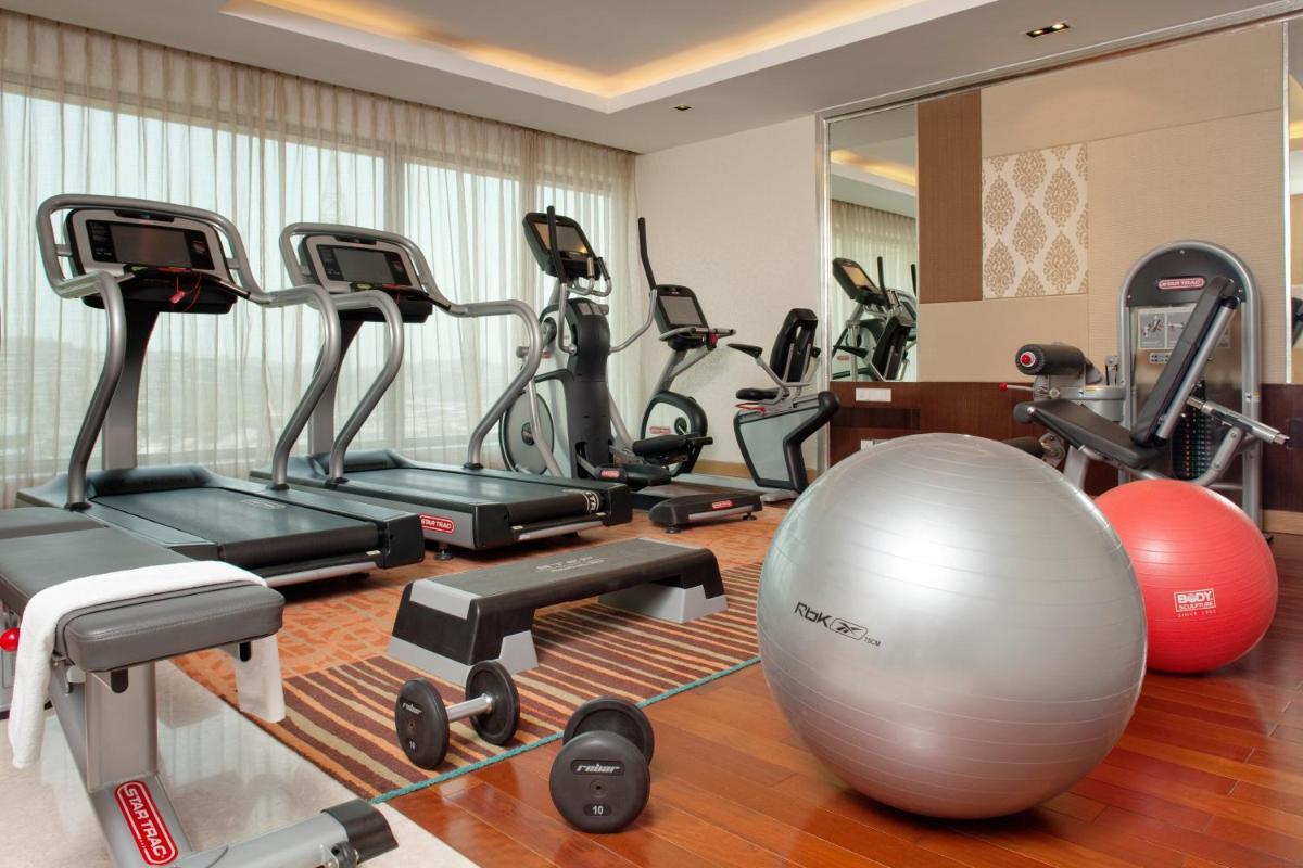 a gym with a bunch of exercise bikes and a ball at Holiday Inn Mumbai International Airport by IHG in Mumbai