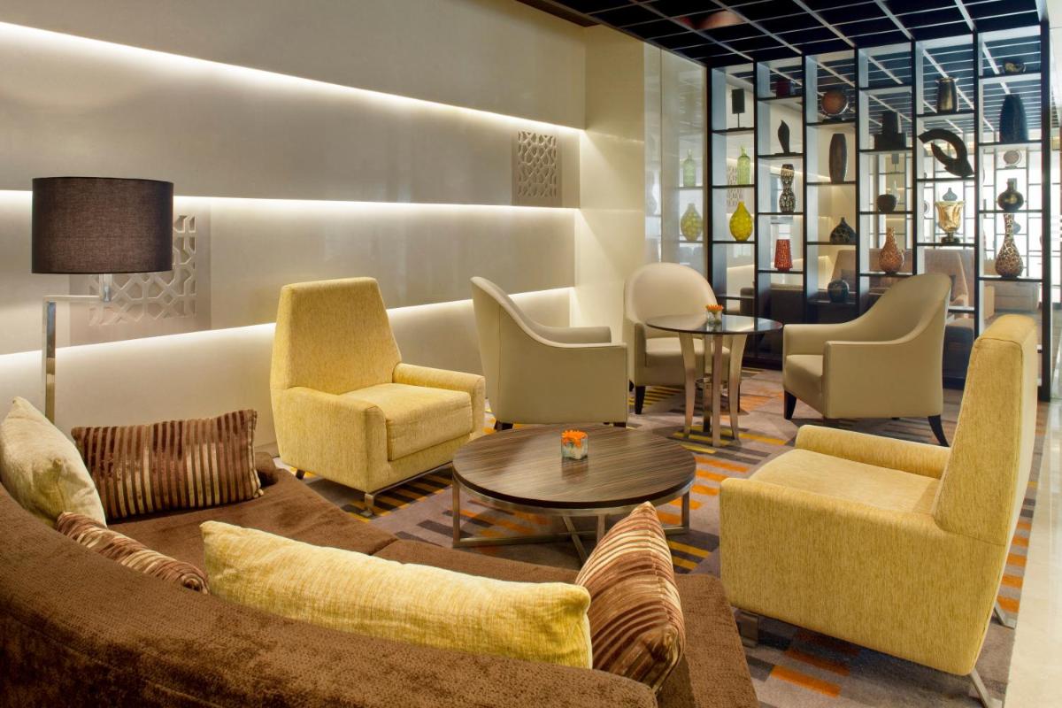 a lobby with a couch and chairs and a table at Holiday Inn Mumbai International Airport by IHG in Mumbai