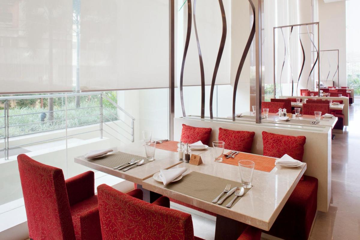 a dining room with a table and red chairs at Holiday Inn Mumbai International Airport by IHG in Mumbai