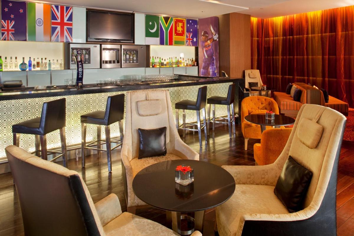 a restaurant with a bar with chairs and tables at Holiday Inn Mumbai International Airport by IHG in Mumbai