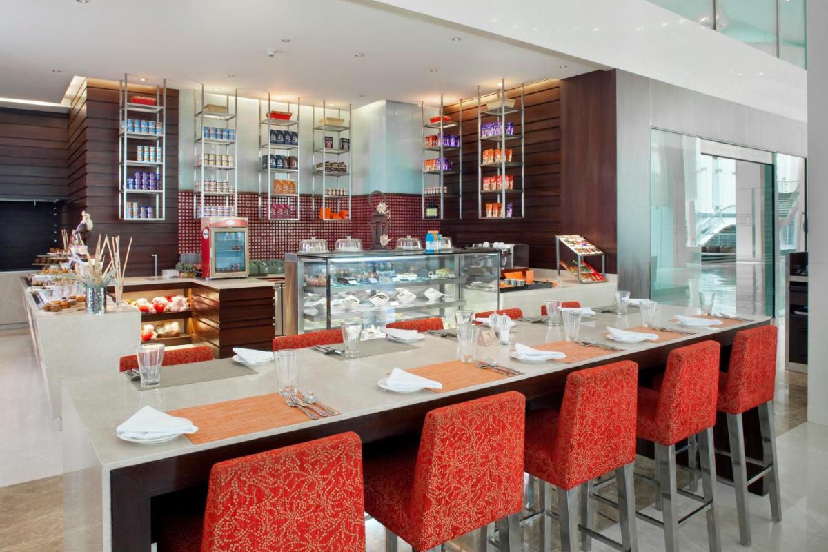 a restaurant with a long table and red chairs at Holiday Inn Mumbai International Airport by IHG in Mumbai
