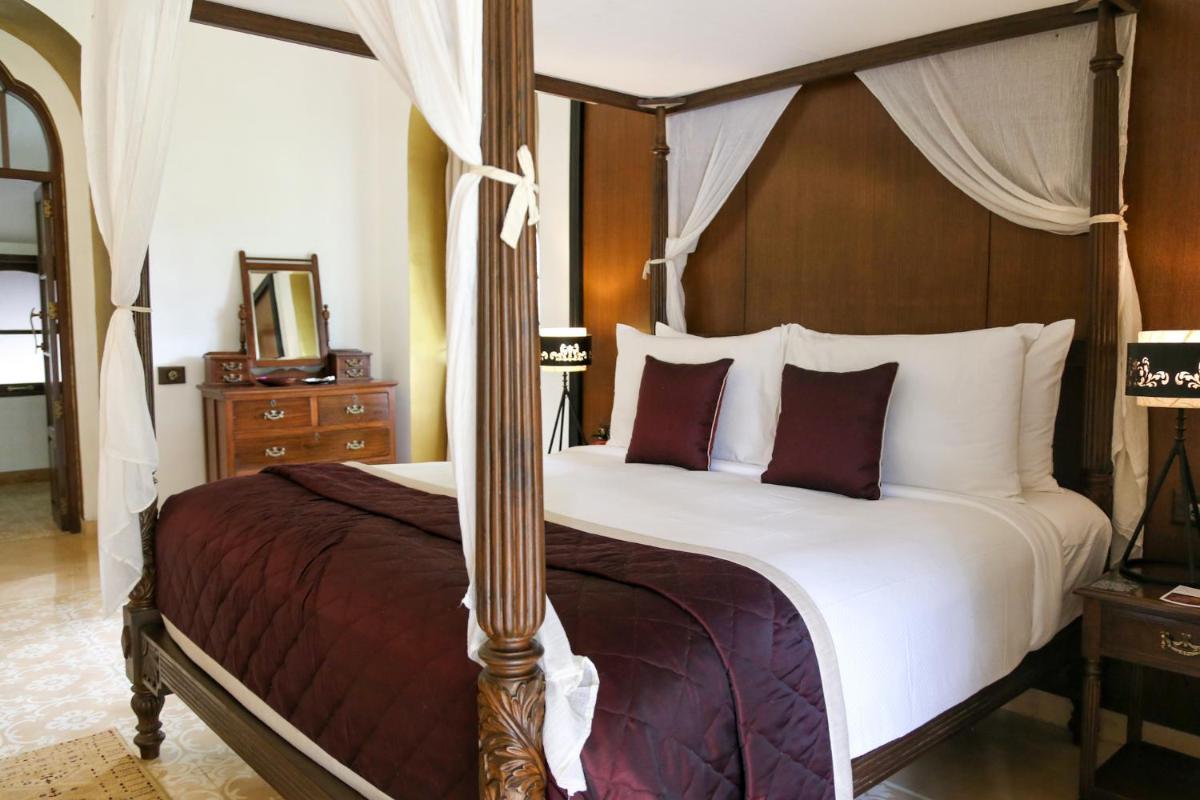a bedroom with a large bed with a canopy at The Postcard Cuelim, Goa in Cansaulim