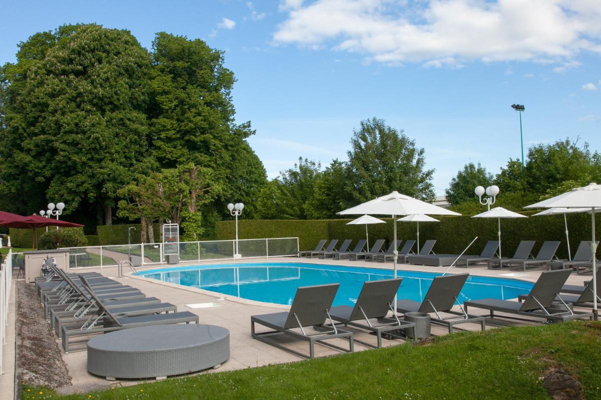 une piscine avec chaises longues et parasols dans l'établissement Hôtel Cosmos & Spa, à Contrexéville
