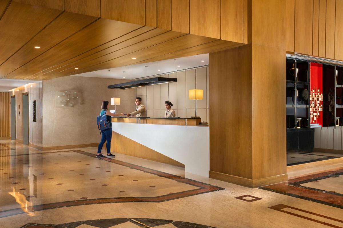 a woman standing at a counter in a hotel lobby at Holiday Inn Agra MG Road an IHG Hotel in Agra