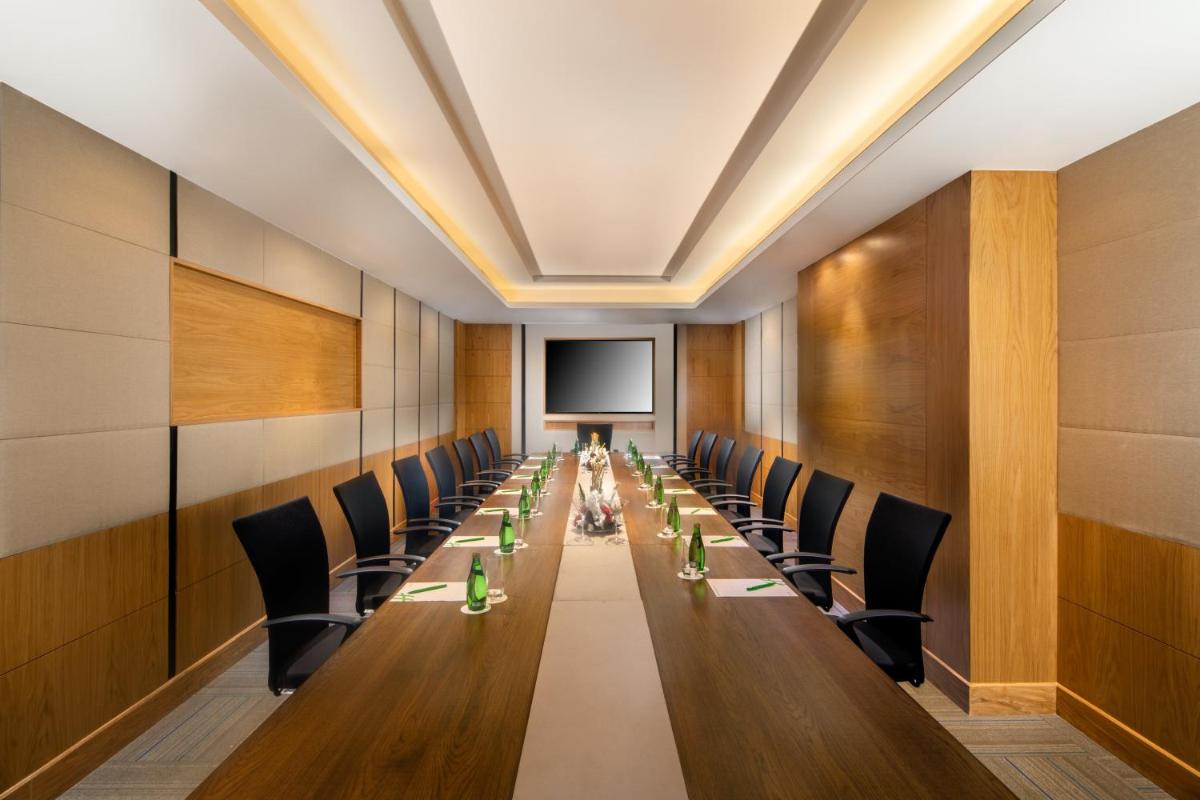 a long table in a room with chairs and a screen at Holiday Inn Agra MG Road an IHG Hotel in Agra