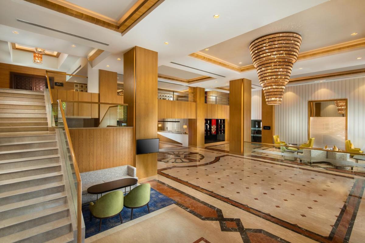 a lobby with a staircase and a large chandelier at Holiday Inn Agra MG Road an IHG Hotel in Agra