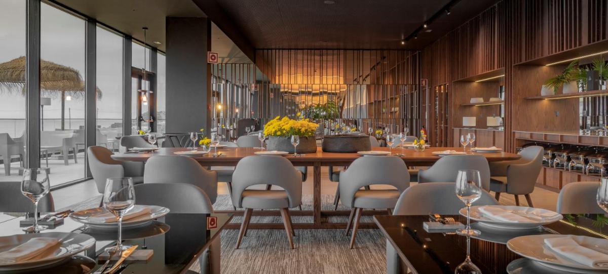 um restaurante com uma mesa longa e cadeiras em Hotel Verde Mar & SPA na Ribeira Grande