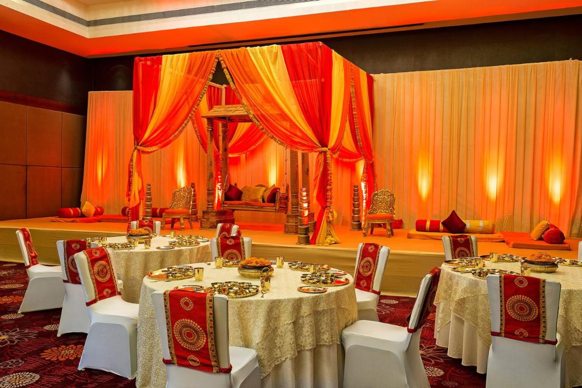 a banquet hall with tables and chairs and curtains at Crowne Plaza Ahmedabad City Centre by IHG in Ahmedabad