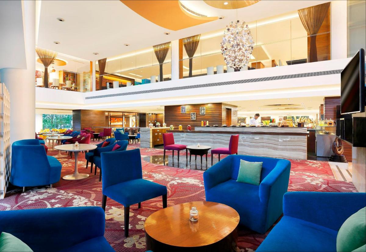 a hotel lobby with blue chairs and tables at Crowne Plaza Ahmedabad City Centre by IHG in Ahmedabad