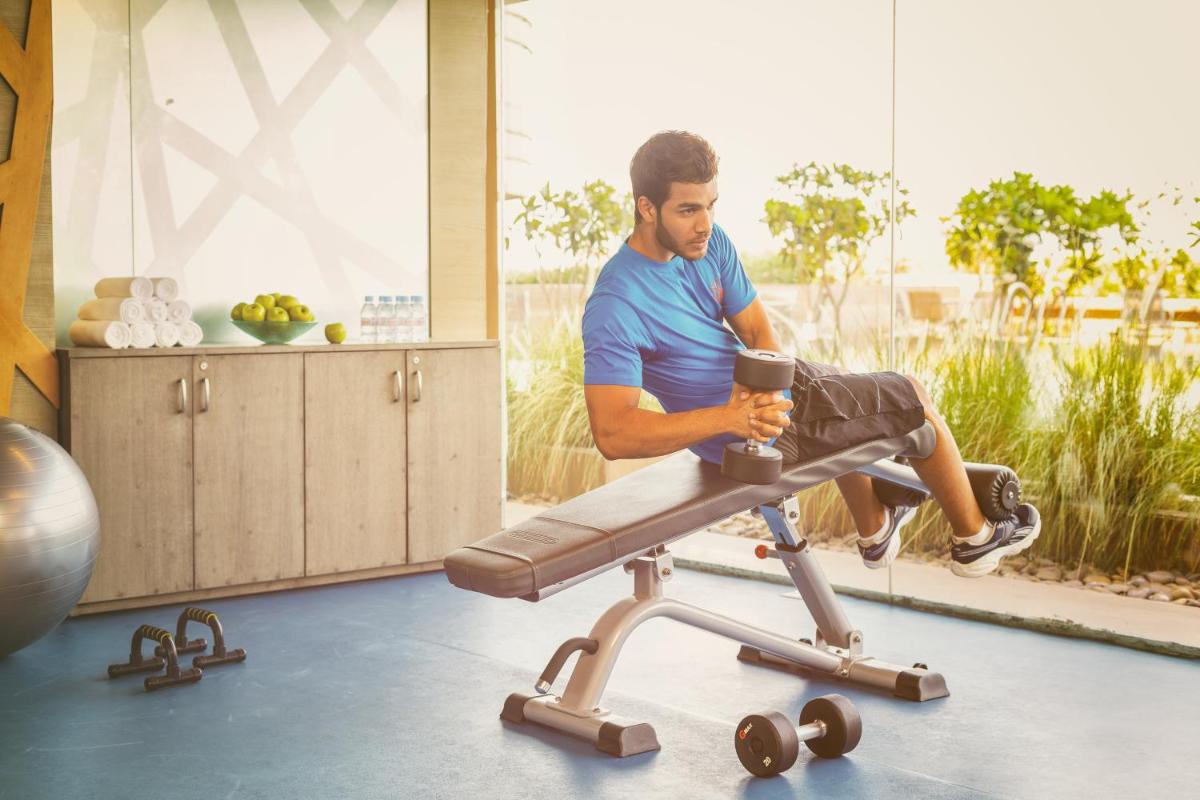 a man sitting on a treadmill looking at his cell phone at Crowne Plaza Ahmedabad City Centre by IHG in Ahmedabad
