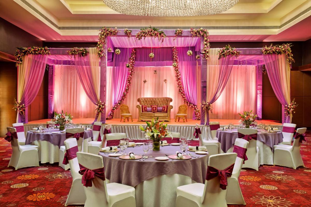 a banquet hall with tables and chairs and pink curtains at Crowne Plaza Ahmedabad City Centre by IHG in Ahmedabad