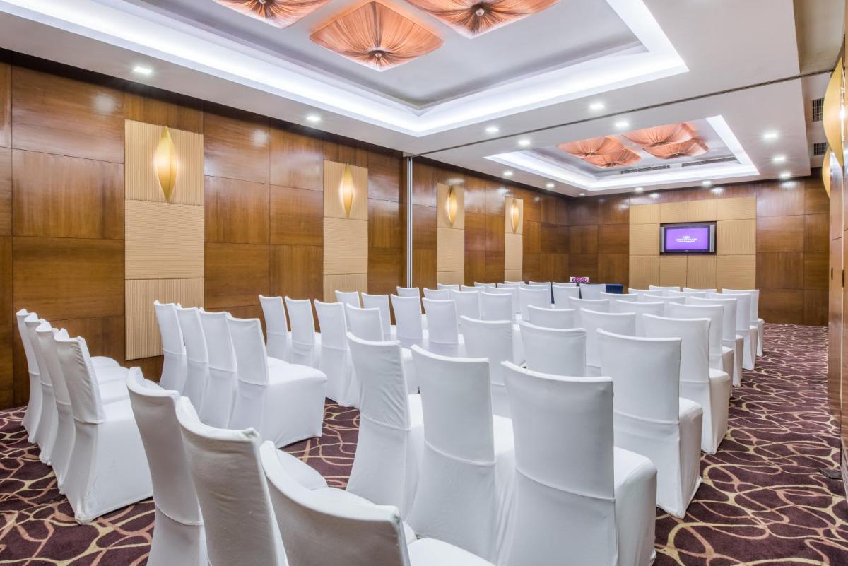 a conference room with white chairs and a wall at Crowne Plaza New Delhi Okhla by IHG in New Delhi