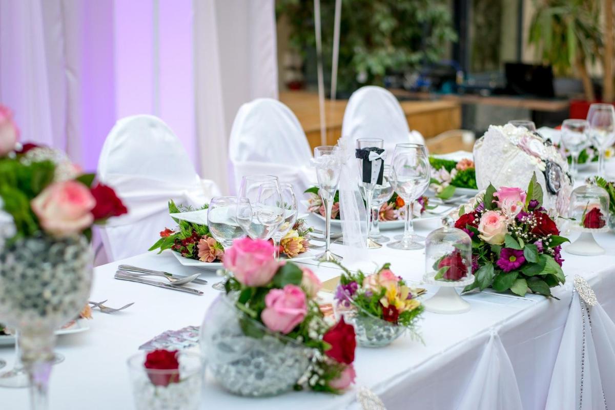 une table avec des chaises blanches et des fleurs dans des vases dans l'établissement Le Nesk Ventoux - Hotel, à Sault