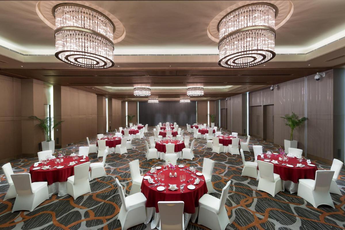 a large room with tables and white chairs and chandeliers at Holiday Inn New Delhi Aerocity by IHG in New Delhi