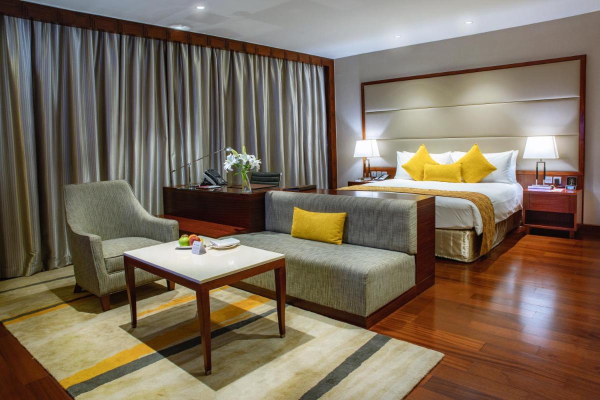a hotel room with a bed and a couch and a table at Crowne Plaza Kochi by IHG in Cochin